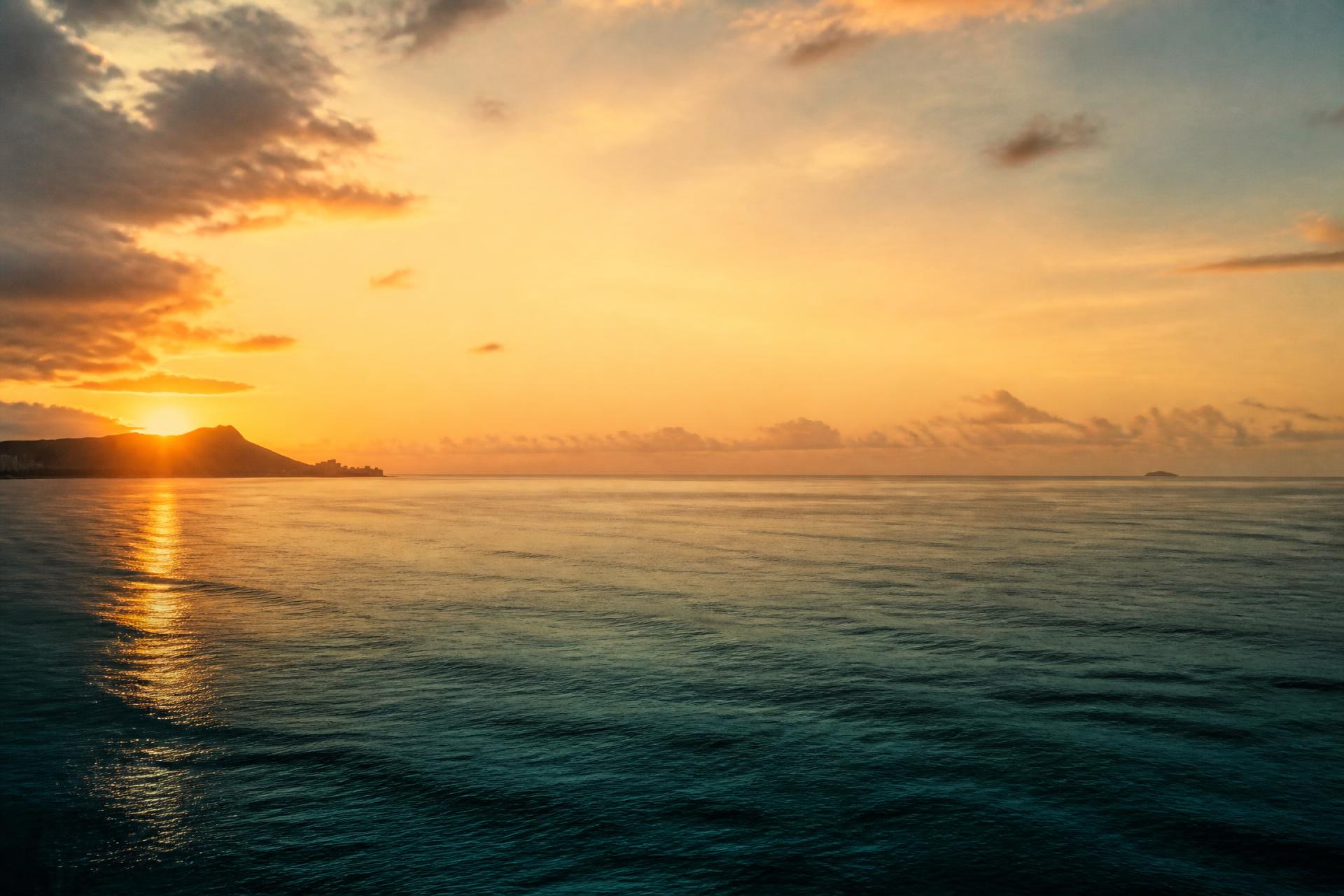 Sunlight reflecting across the ocean beneath warm clouds
